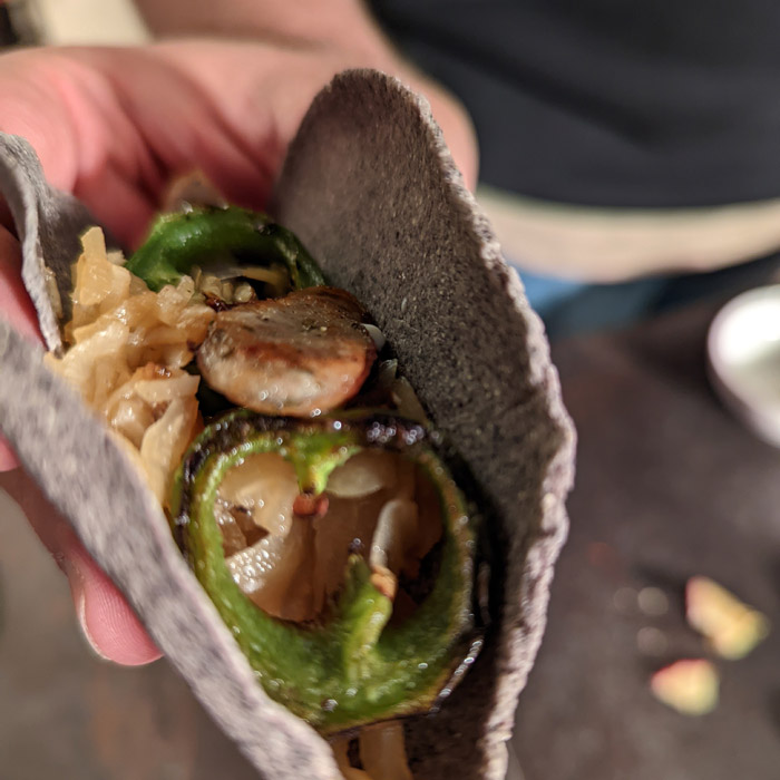 Sauerkraut Tacos mit Würstchen und Apfelmus Joghurt Dressing auf dunklem Teller