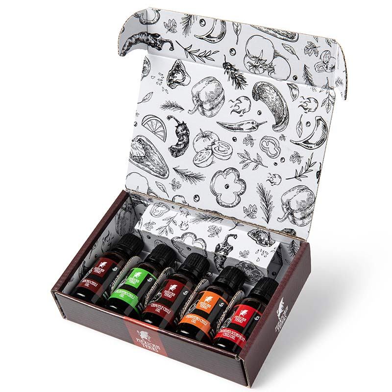 Chiliöl Geschenkset – 5 Sorten von mild bis extrem scharf in stilvoller Box Offene Geschenkbox von Mexican Tears mit fünf kleinen Flaschen Chiliöl: Jalapeño, Ancho, Chipotle, Habanero und Trinidad Scorpion. Die Innenverpackung ist mit schwarz-weißen Illustrationen von Chilis und Gewürzen verziert.
