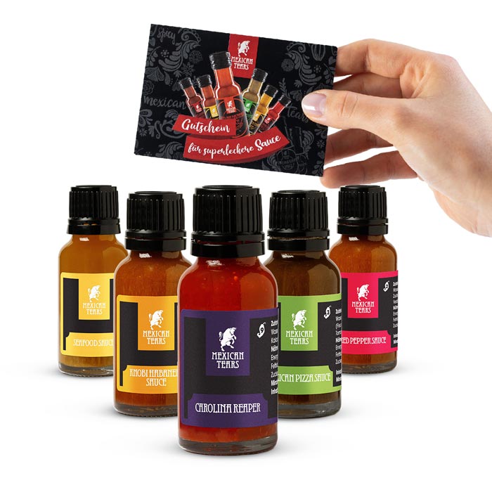 Gutschein Box mit kleiner Probierbox Eine Hand hält einen Gutschein vor eine Gewürzflasche mit der Aufschrift